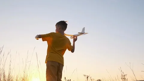Slow motion boy summer meadow against sunset holds a white plane Stock Footage 116473000