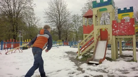 Slow motion. The boy throws snow on the playground. Video stock 74869567