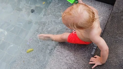 Slow motion. boy of two years playing with a toy, sitting in the pool.  Stock Footage 104698517