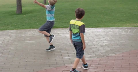 Slow Motion Boys Jumping and Playing on Pavement in Park Stock Footage 61716094