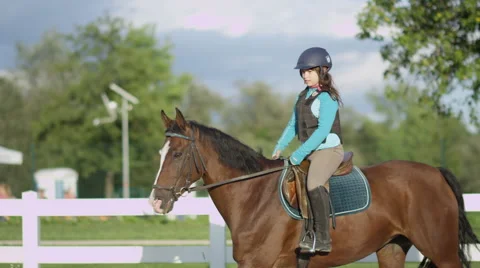 SLOW MOTION: Brave happy little girl horseback riding big strong brown horse Stock Footage