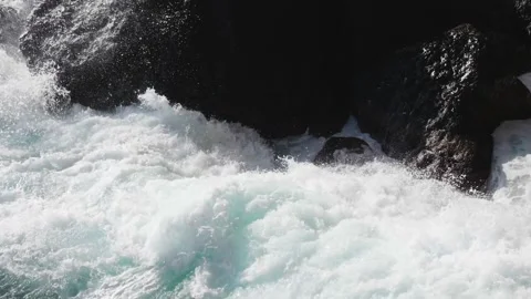 Slow motion. Bright blue waves break into white foam on the coastal rocks along Stock Footage 259538641