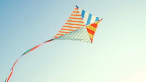 Slow motion a bright kite with a long tail of silk ribbons flies in a light wind Stock Footage 94449356