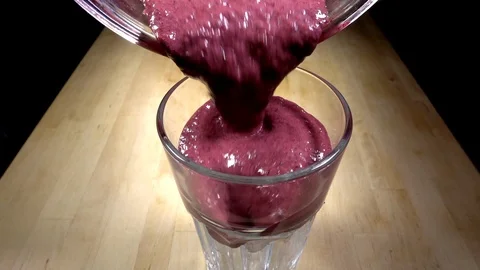 Slow motion - Bright pink thick fruit smoothie pouring into tall glass with ice. Stock-Footage 114008843