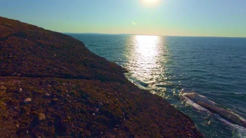 Slow motion bright sunlight reflection on ocean surface near rocky coast Stock Footage 340451917