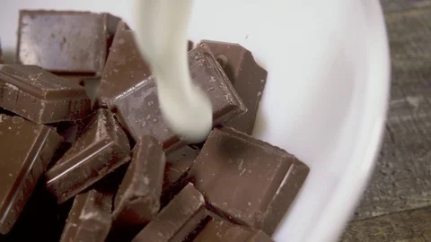 Slow motion broken chocolate pour milk close-up Stock Footage 95394447