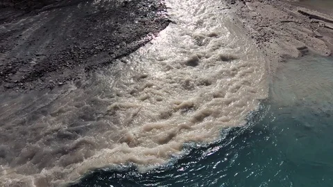 Slow motion brown and clean green water mixing together in Alpine river stream Stock Footage 121513262