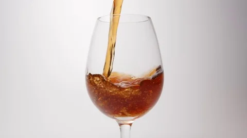 SLOW MOTION: Brown beverage pour into a glass on a white background Stock Footage 70804531
