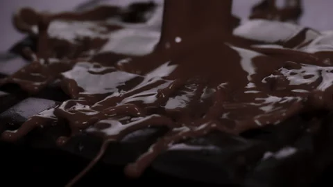 Slow motion: Brown, chocolate liquid pouring over chocolate slab. UHD25p Stock Footage 249598581