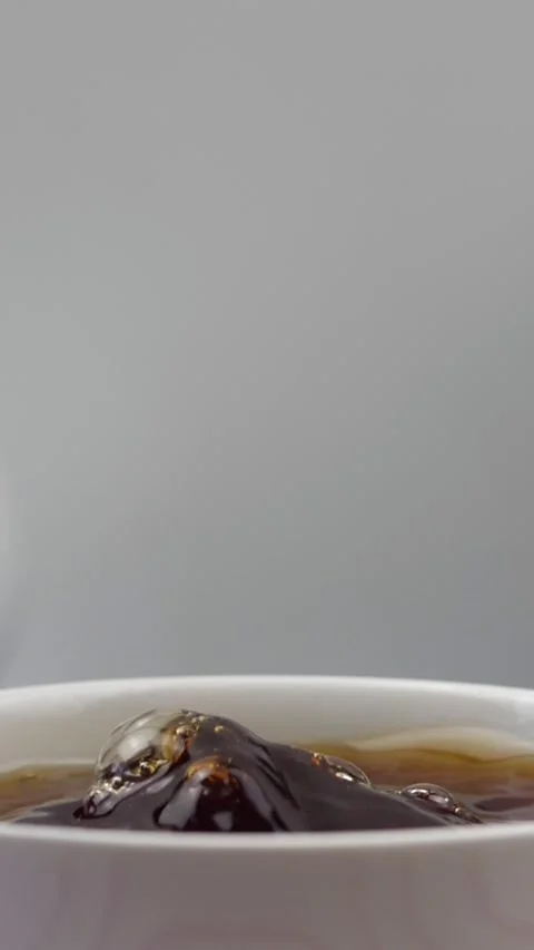 Slow motion of a brown sugar cube falling into a cup of tea Stock Footage 307811394