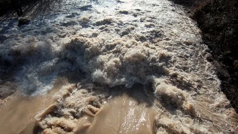 Slow motion brown wild chaotic dirty water flood river banks Stock Footage 121680060