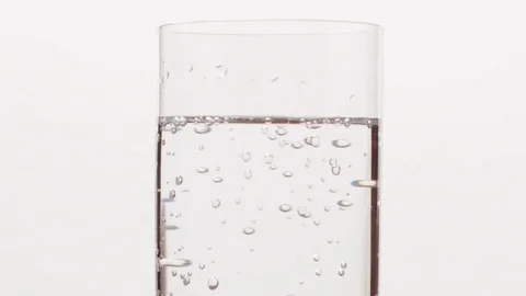 Slow motion bubbles in mineral water in glass over white background Stock Footage