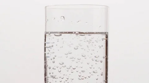 Slow motion bubbles in mineral water in glass over white background Stock Footage