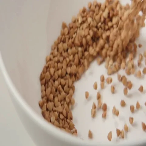 SLOW MOTION: Buckwheat fall on white dish (close up) Stock Footage 69477193