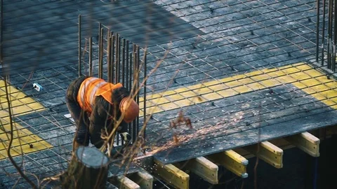 Slow motion builder cuts rebar with an angle grinder at construction site Stock Footage