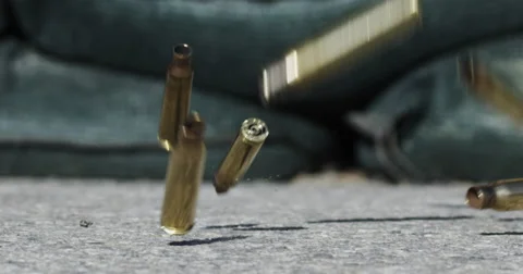 Slow motion bullet casings bouncing in front of sand bags Stock Footage 45976393