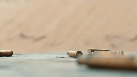 Slow Motion Bullet Casings Falling on Wooden Table in Dusty Environment Stock Footage 267951667