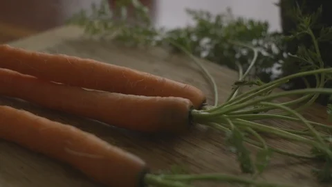 Slow motion bunch of carrots picked up and tossed onto cutting board Stock-Footage 88407236
