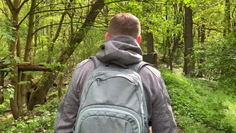 Slow motion camera follows man hiker in grey hooded jacket with backpack. Att Stock Footage 240849221