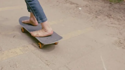 Slow motion, the camera follows the ride of a barefooted boy on a skateboard. Видео 72319062