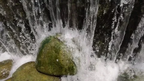 Slow motion camera moves up to the splash of clear river water falling on th Video stock 321845321