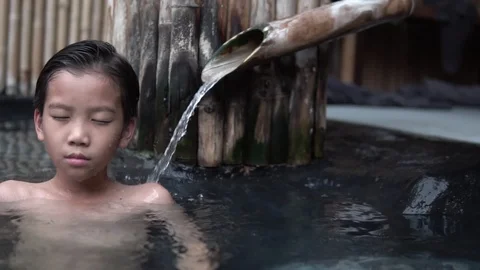 Slow motion of camera pan from right to left at young boy relax in hot water Stock Footage 122101717