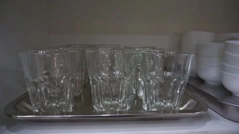Slow motion camera panning of clean empty glass tumblers arranged on a stainless Stock Footage 341514000