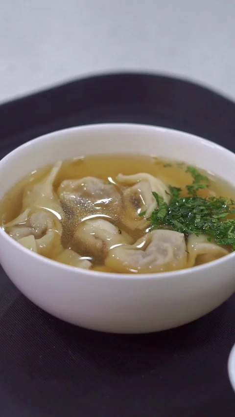 Slow motion camera panning of traditional uzbek chuchvara dumpling soup served w Stock Footage 342345269