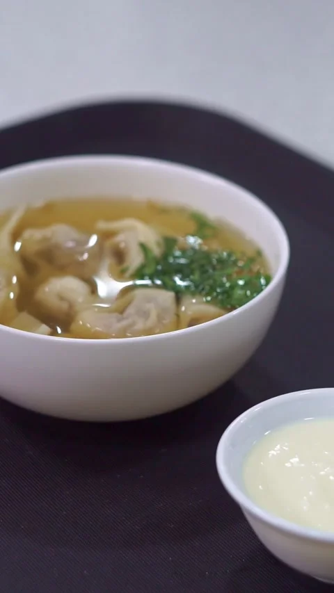 Slow motion camera panning of traditional uzbek chuchvara dumpling soup served w Stock Footage 342345270