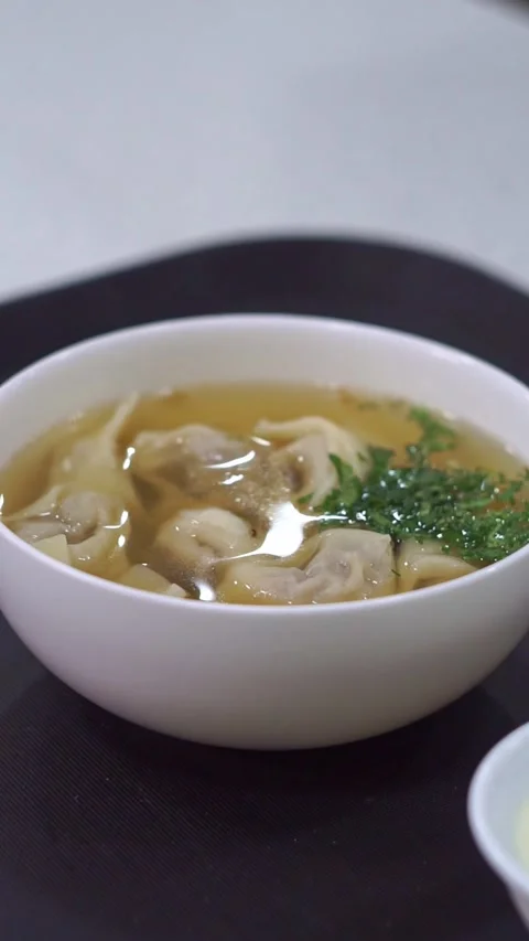 Slow motion camera panning of traditional uzbek chuchvara dumpling soup served w Stock Footage 342345271