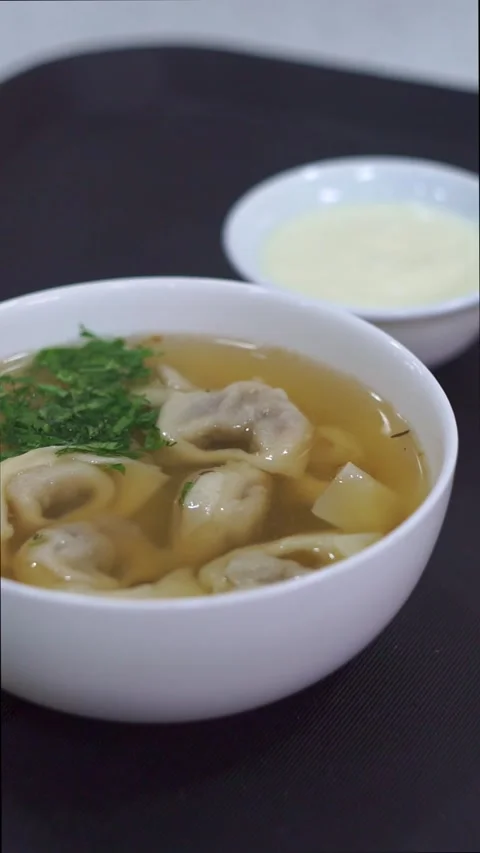Slow motion camera panning of traditional uzbek chuchvara dumpling soup served w Stock Footage 342345281