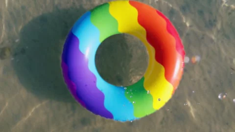 Slow Motion Camera Passing Through the Center of a Colorful Inflatable Swim Ring Stock Footage 339009861
