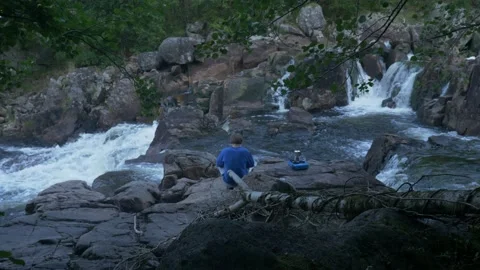 Slow motion camera view of man sitting on the rocks next to the mountain river Stock Footage 237925303