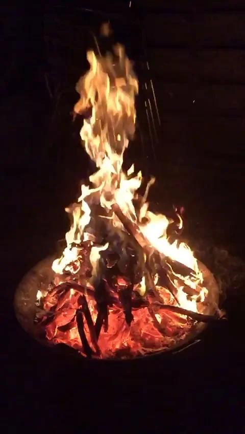 Slow motion of a camp fire at night in a fire bowl, with red hot ambers Stock Footage