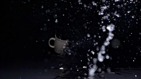 Slow-motion capture of a light-colored mug breaking on impact with the floo.. Video stock 298181914