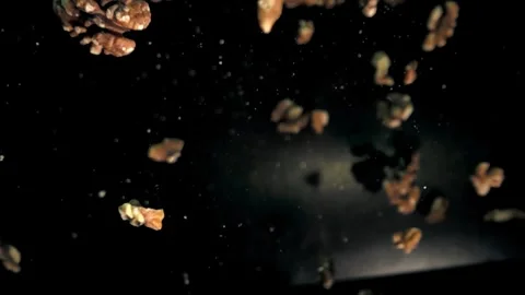 Slow Motion Capture of Walnut Pieces Falling Against a Dark Background Video stock 272190448