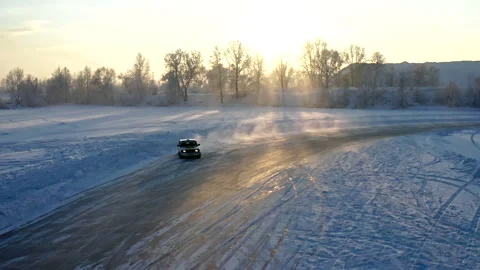 Slow motion of a car drifting on a winter ice road at sunset. Stock Footage 169452420