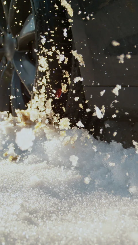 SLOW MOTION: Car driving off road on sunny day spitting up pieces of wet snow. Stock Footage 305574565