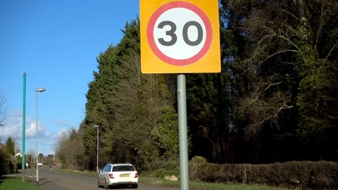 Slow motion – Car passing a 30 speed limit sign on entering a village. Stock Footage 104763322