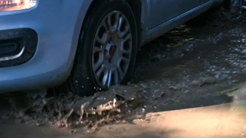 Slow motion of car passing over a mud puddle dirty road Stock Footage 224385952