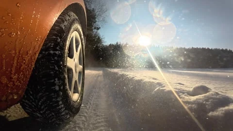 Slow motion car wheel driving through snowy rural road in winter sunlight Stock Footage 329011945