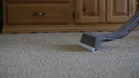 Slow motion carpet cleaner moving over tan carpet in front of wood dresser Video stock 85870704