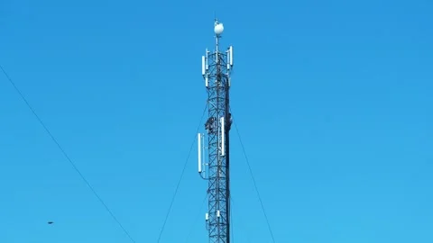 Slow Motion Cell tower on blue background. A bird flies near a cell phone tower Stock Footage 318251051