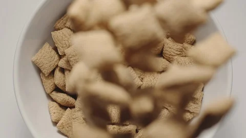 SLOW MOTION: Cereal bites falling into a white bowl Stock Footage 108573457