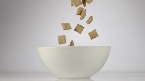 SLOW MOTION: Cereal bites falling in a white dish on a table Vídeos de archivo 108959587
