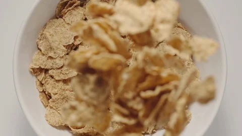 SLOW MOTION: Cereal flakes falling into a white bowl Vídeos de archivo 108573421