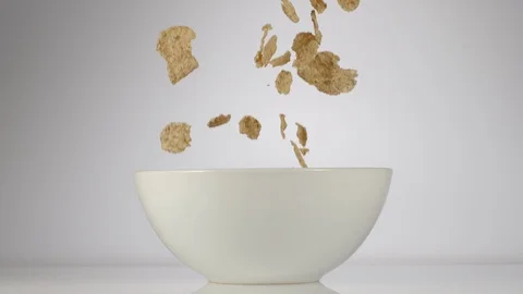 SLOW MOTION: Cereal flakes falling in a white dish on a white background Stock Footage 108959548