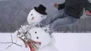 Slow Motion: Cheerful Guy Destroying A Snowman On Snowy Field In White Winter. Stock Footage