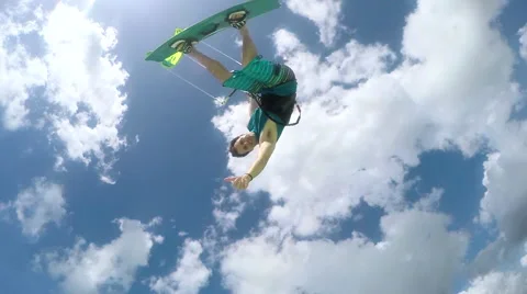 SLOW MOTION: Cheerful kite surfer jumping high over camera showing shaka sign Stock Footage 66491227