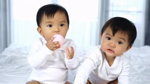 Slow-motion of cheerful twin babies playing color ball on a bed Stock Footage 112637922